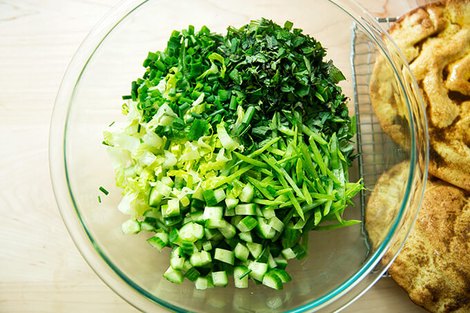 All the green ingredients for the fattoush salad, chopped and in a bowl: Romaine, mint, chives, snow peas, cucumbers.