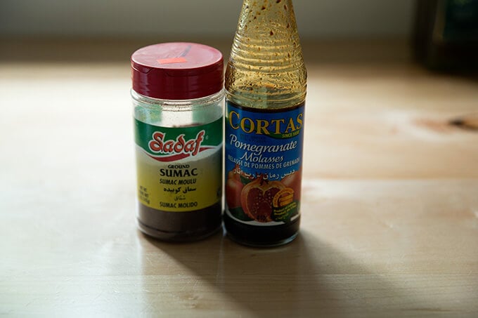 A jar of sumac and a bottle of pomegranate molasses sitting on the counter.