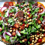 A plate of Israeli-spiced tomato and chickpea salad with cucumber-yogurt sauce.