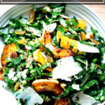 A bowl of raw collard green salad with roasted delicata squash, toasted almonds, golden raisins, and shaved parmesan.