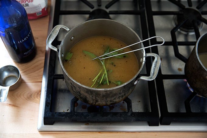A saucepan filled with gravy simmering with sage.