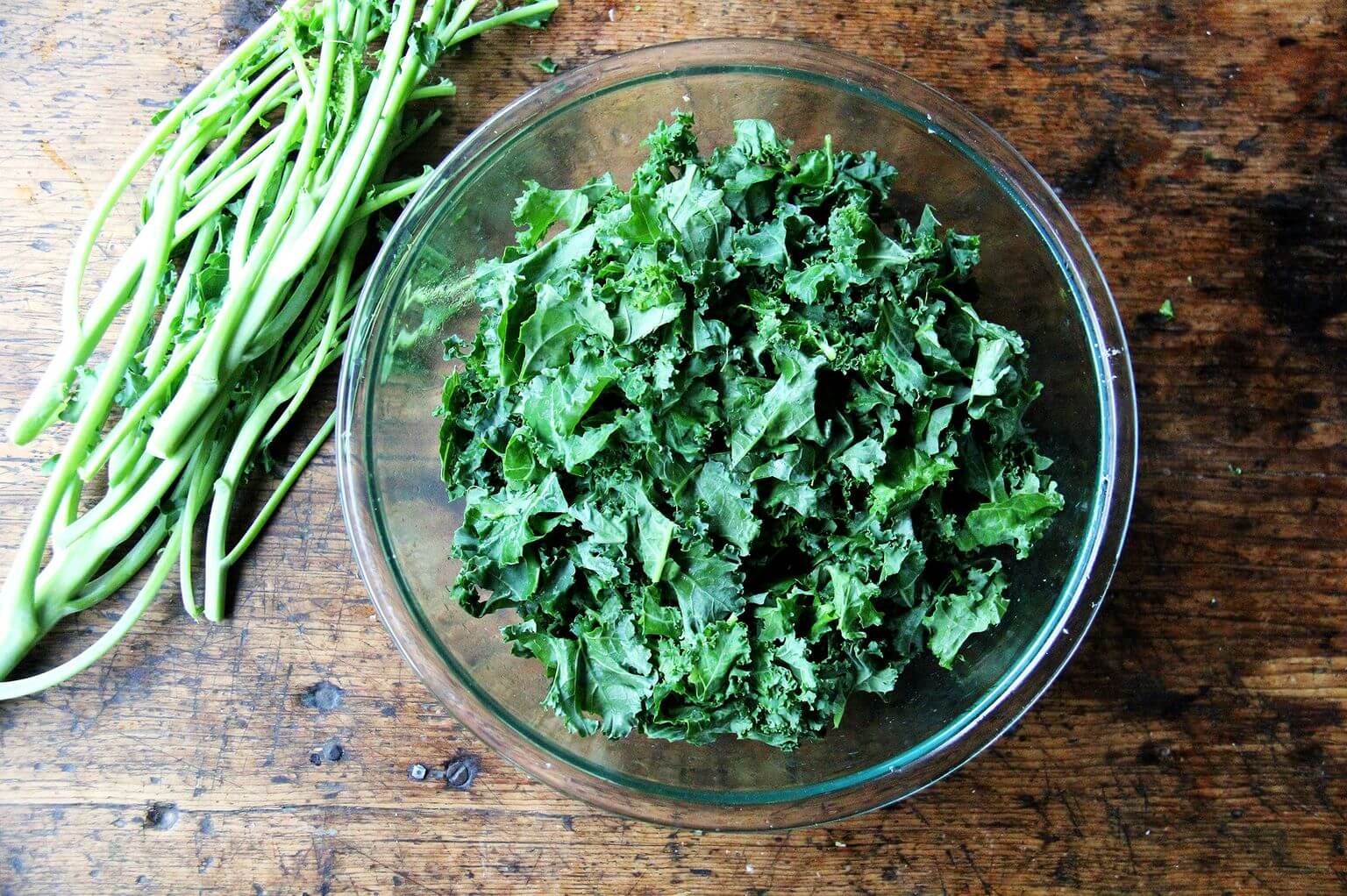 An overhead shot of a glass bowl filled with kale.