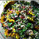 A white serving bowl filled with winter tabbouleh and roasted delicata squash slices.
