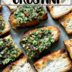 Sun-dried tomato and spinach pesto spread on crostini on a sheet pan.