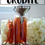 Pickled crudité in glass jars, one with a funnel.