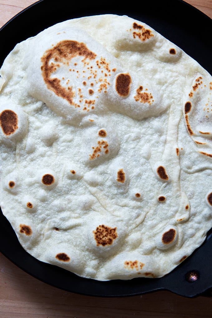 A homemade flour tortilla in a skillet.