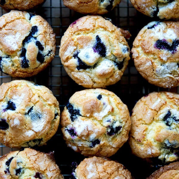 An overhead shot of a dozen blueberry muffins on a cooling rack.