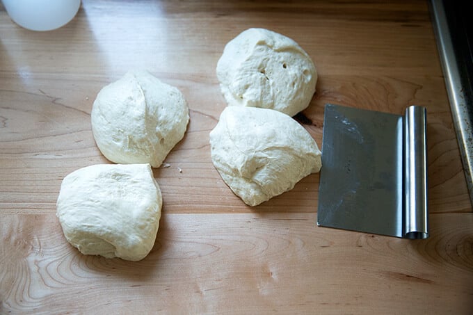 Portioned sourdough pizza dough aside a bench scraper.