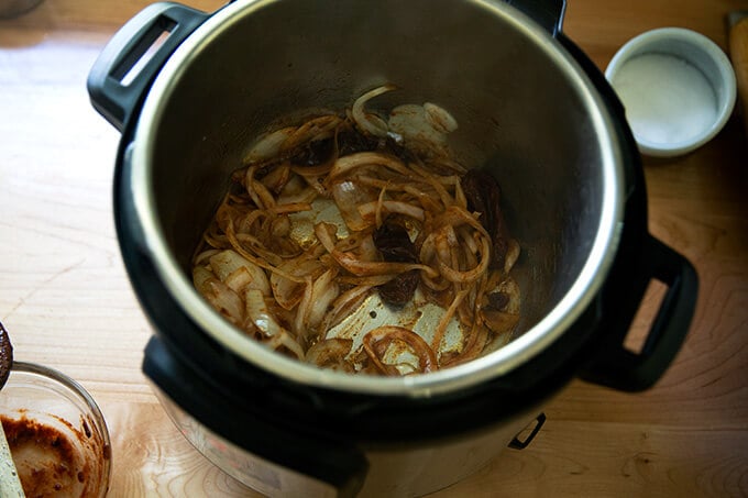 An Instant Pot filled with sautéed onions and chipotle in adobo sauce.