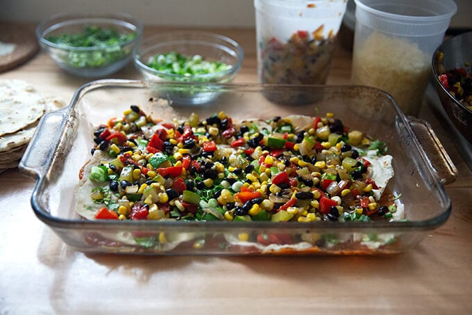 Layering the enchilada casserole with tortillas and summer vegetables.