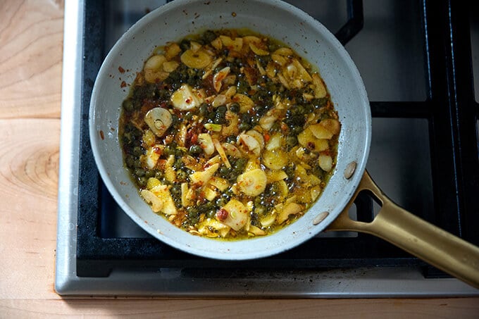 Sizzling oil in a skillet with garlic, capers, and Calabrian chili paste.