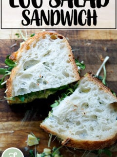 An egg salad sandwich on a board.