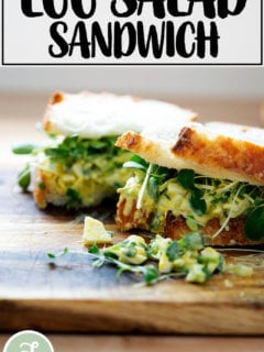 An egg salad sandwich on a board.
