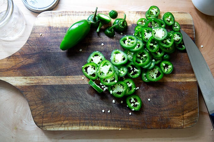 Sliced jalapeƱos on a board.