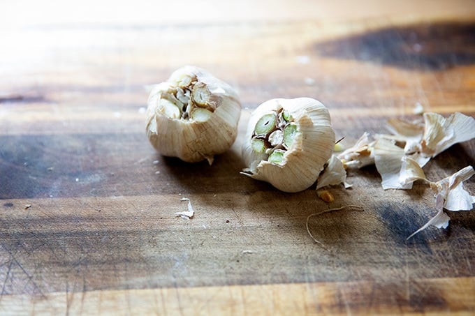 Two heads of garlic on a board.