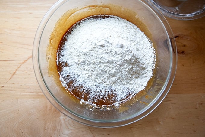 Adding the flour to the bowl of gingerbread cookie bars batter in the making.