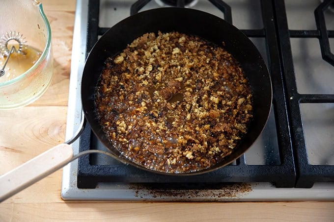 A skillet filled with crisped tofu crumbles and miso-lime sauce.