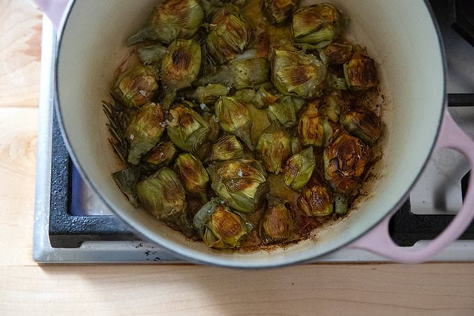 A large pot filled with baby artichokes crisped up and finished cooking on the stovetop.
