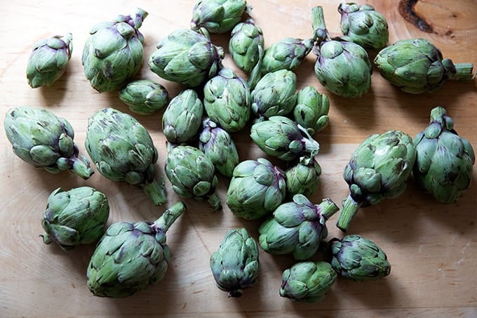 A countertop topped with a couple of pounds of baby artichokes.