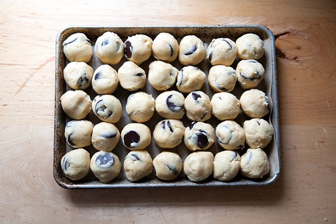 A small sheet pan filled with chocolate chip cookie dough balls.