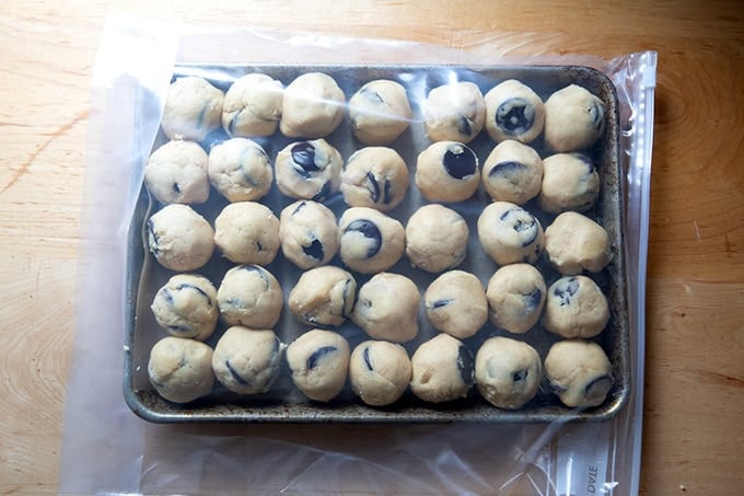 A small sheet pan filled with chocolate chip cookie dough balls tucked inside a ziplock bag.