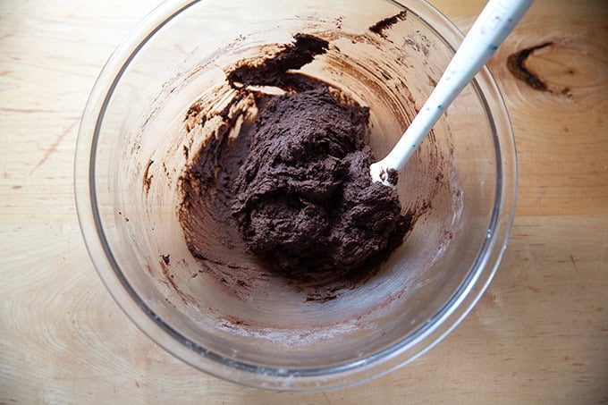 A bowl of chocolate crinkle cookie dough mixed together.