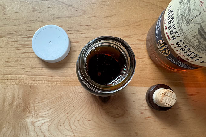 Bourbon poured into a jar filled with small vanilla pods.