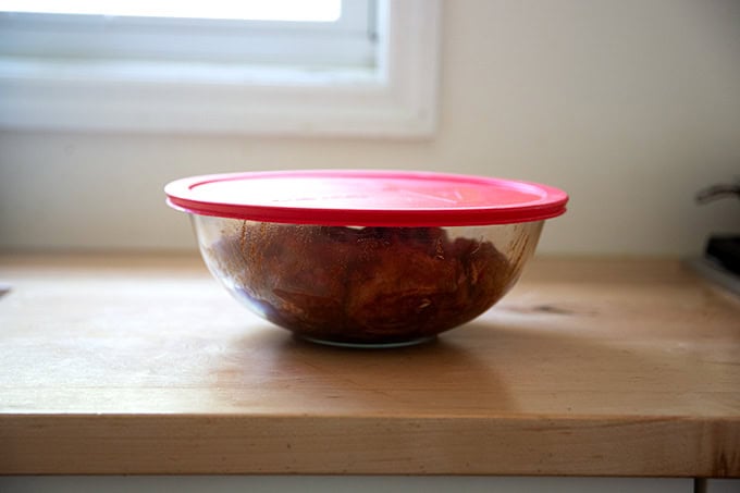 A bowl of marinating chicken covered.