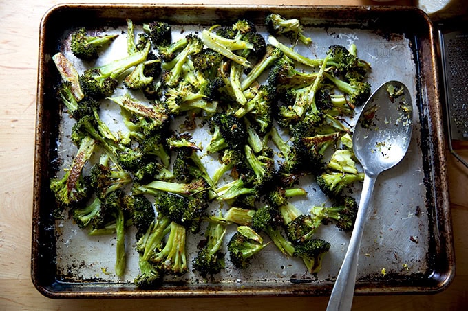 A sheet pan filled with roasted broccoli tossed with parmesan and lemon.