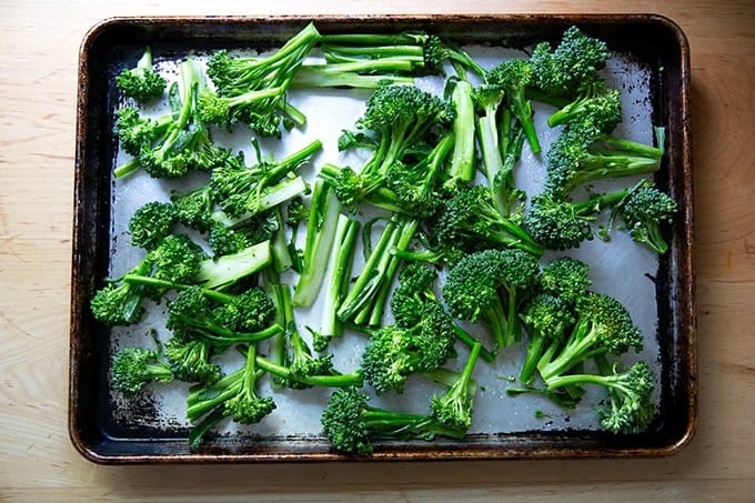 Broccolini tossed with olive oil and salt on a sheet pan.