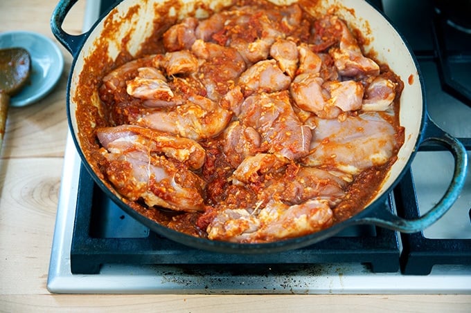 A braiser filled with the ingredients to make butter chicken on the stovetop.