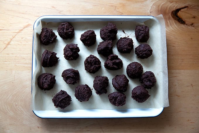 Portioned chocolate crinkle cookie dough balls on a small tray.