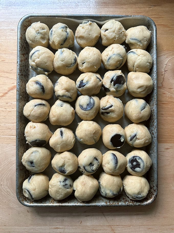 A tray of unbaked chocolate chip cookie dough balls.