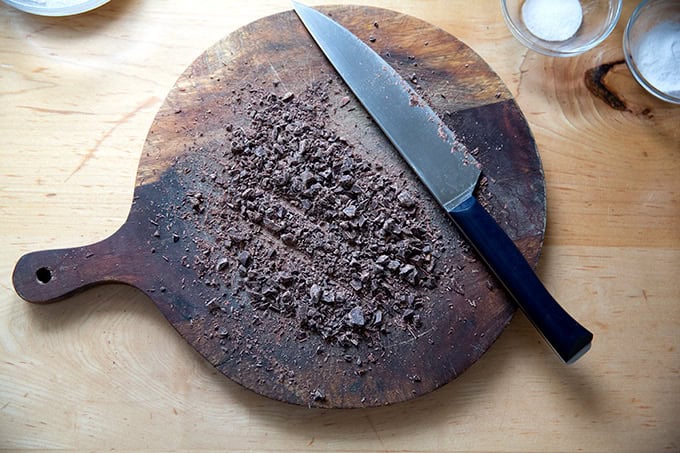 A board with chopped chocolate on top.
