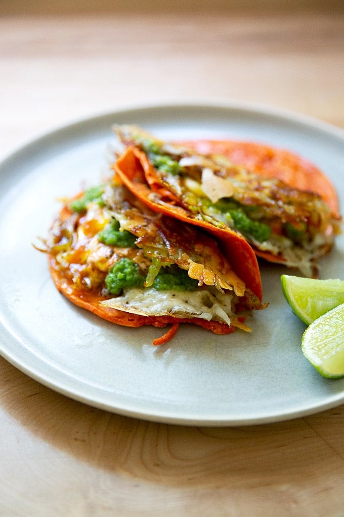 A plate of crispy potatoes, egg, and cheese on tortillas.