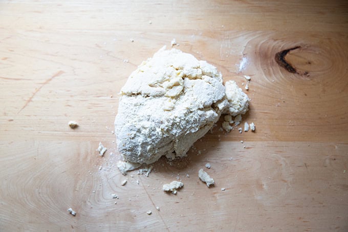 Crumbly hot cross bun dough on a countertop ready to be kneaded.