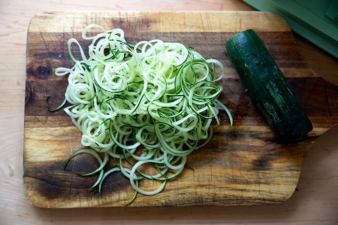 Spiralized cucumbers on a cutting board.