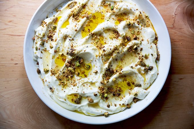 A platter of whipped ricotta with honey, olive oil, and pistachios on top.