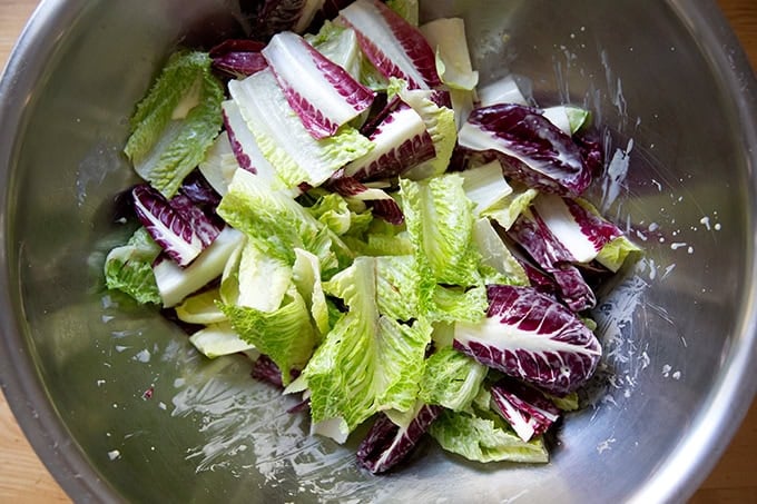 A large bowl of various lettuces dressed in Caesar dressing.