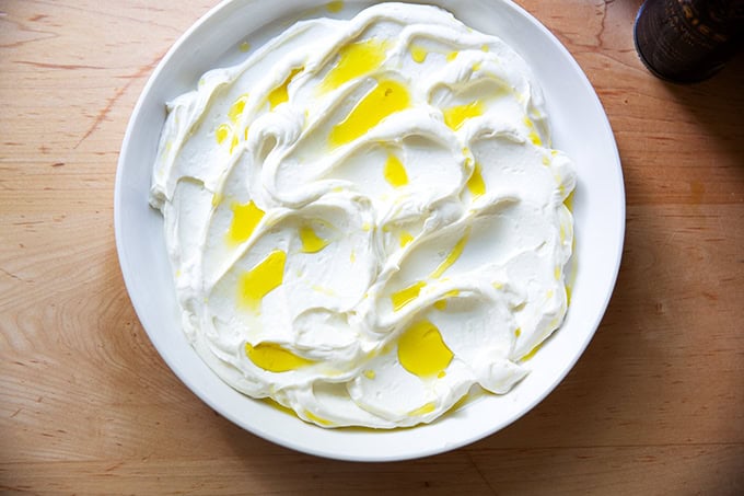 A platter spread with whipped ricotta and drizzled with olive oil.
