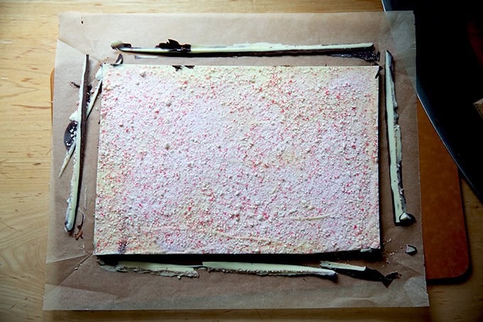Edges trimmed from the peppermint bark on a cutting board.
