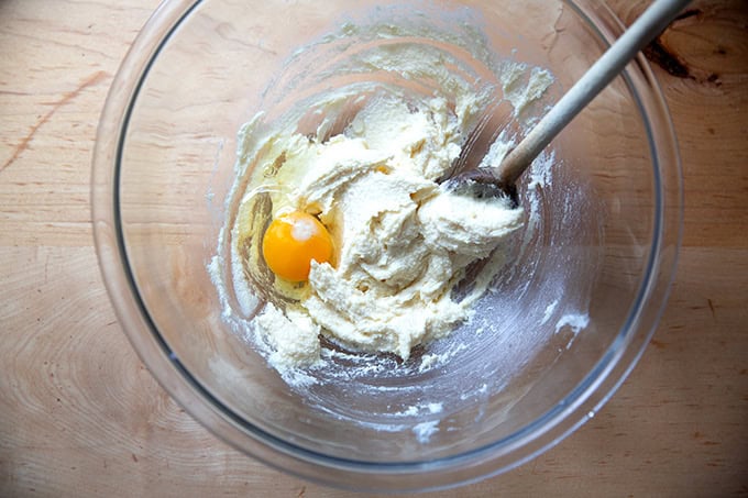 A bowl of creamed together butter and sugar with an egg added.