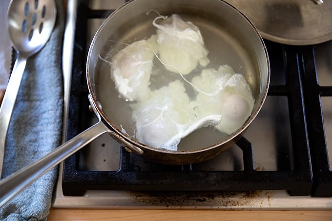 A shallow pot holding water and 4 poached eggs.