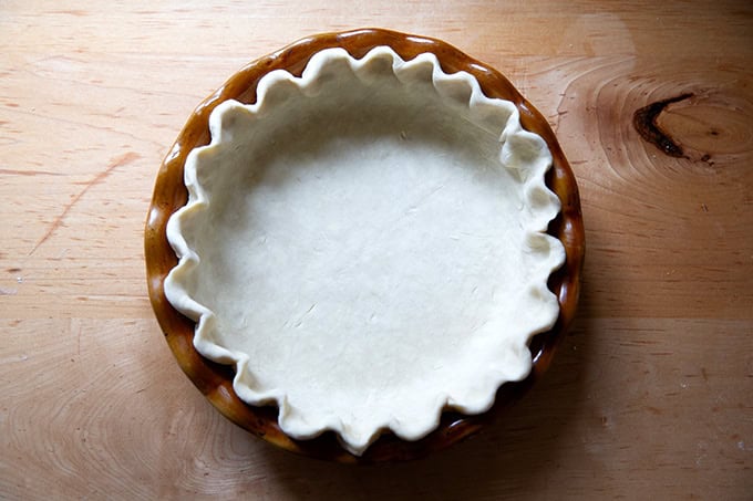 A pie plate fitted with pie dough, its edges crimped.