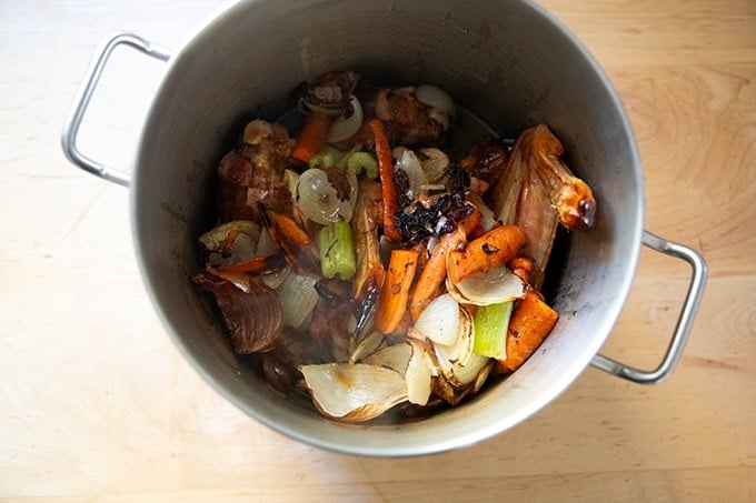 The ingredients to make turkey stock in a large pot along with the deglazed ingredients from the roasting pan.