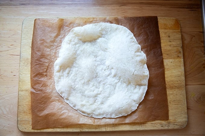 A parbaked gluten-free pizza crust on a cutting board.