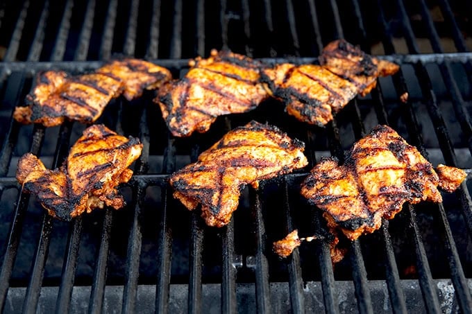 Six chicken thighs on a gas grill.
