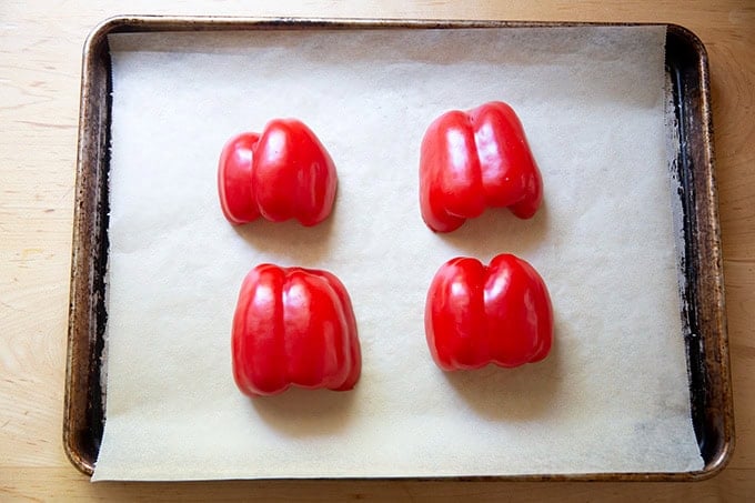 A sheet pan topped with 4 halved red bell peppers.