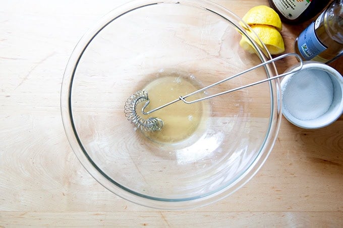 A large bowl filled with honey, white balsamic vinegar, fresh lemon juice, and salt all whisked together.