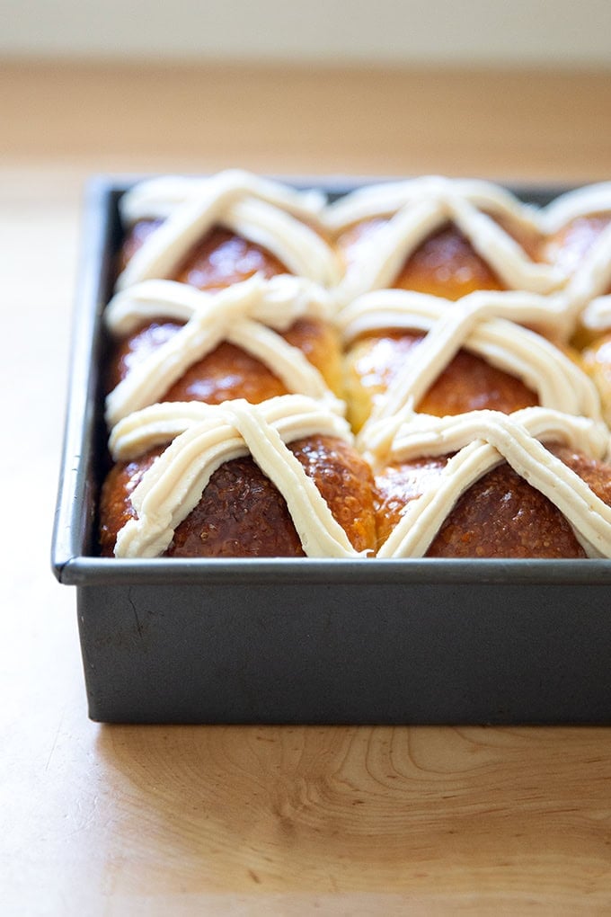 A sideview of a pan of hot cross buns.